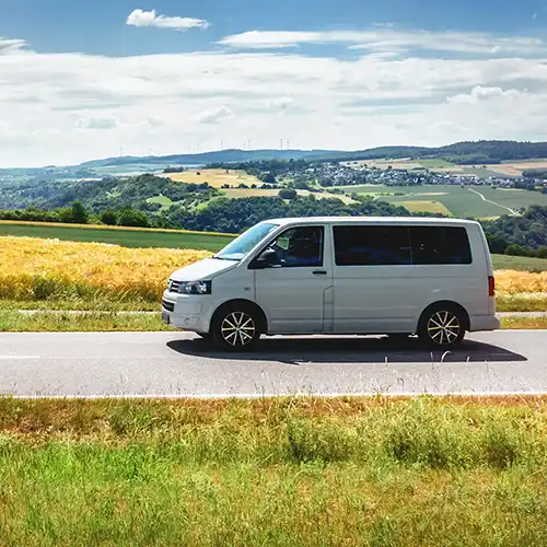 Moderner weisser Kleinbus Camper Seitenansicht vor Landschaft im Sommer im Gegenlicht